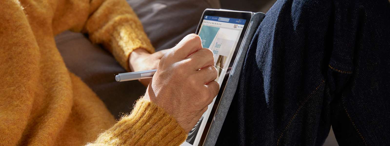 一位男性和一位女性坐在咖啡厅里，女性在触控 Surface Go 2 的屏幕