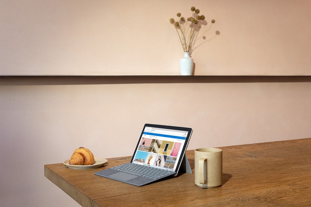 一位女性手持垂直平板电脑模式的 Surface Go 2