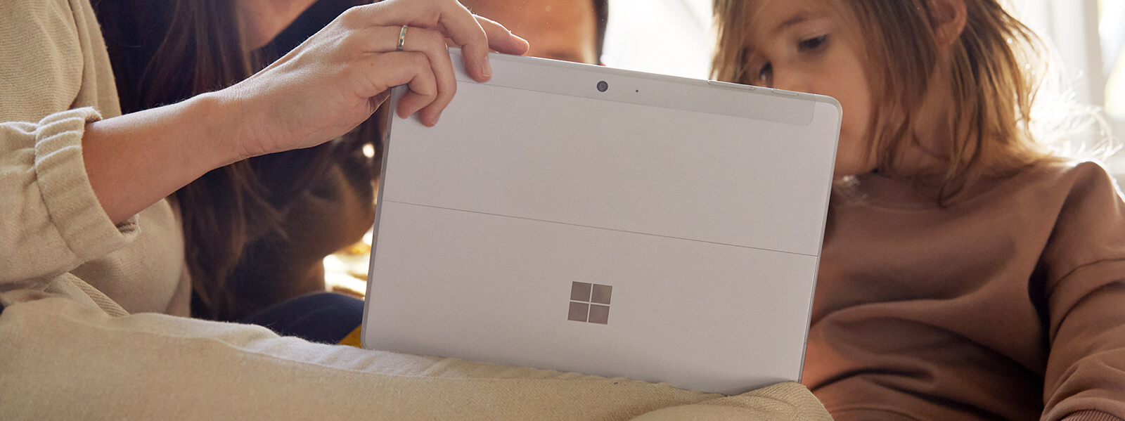 一位女性手持垂直平板电脑模式的 Surface Go 2