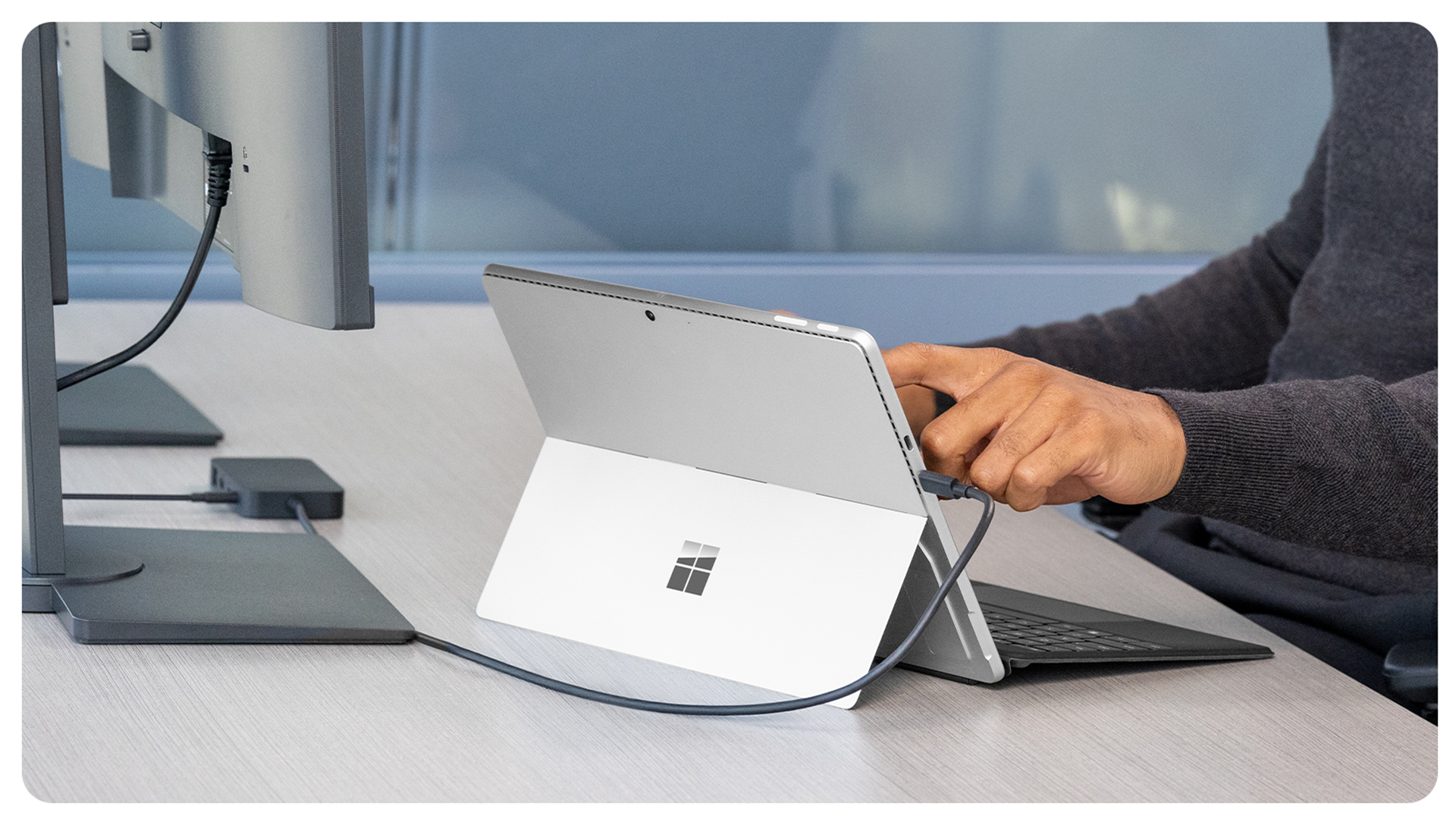 一个人在办公桌前将 Surface Pro 连接到 Surface USB4 扩展坞。 