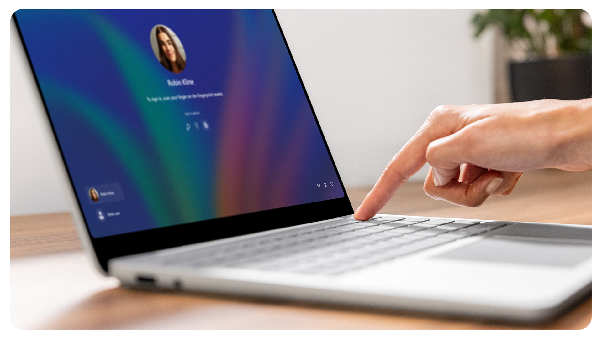 一个人在使用指纹电源按钮登录 Surface Laptop 商用版。