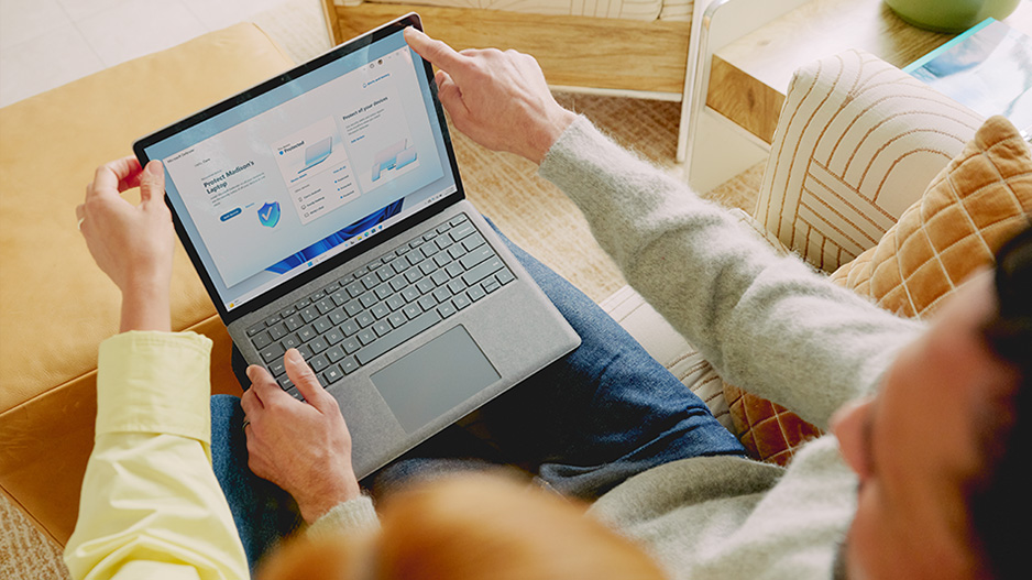两个人在观看一台受 Microsoft Defender 保护的 Surface 设备的屏幕。