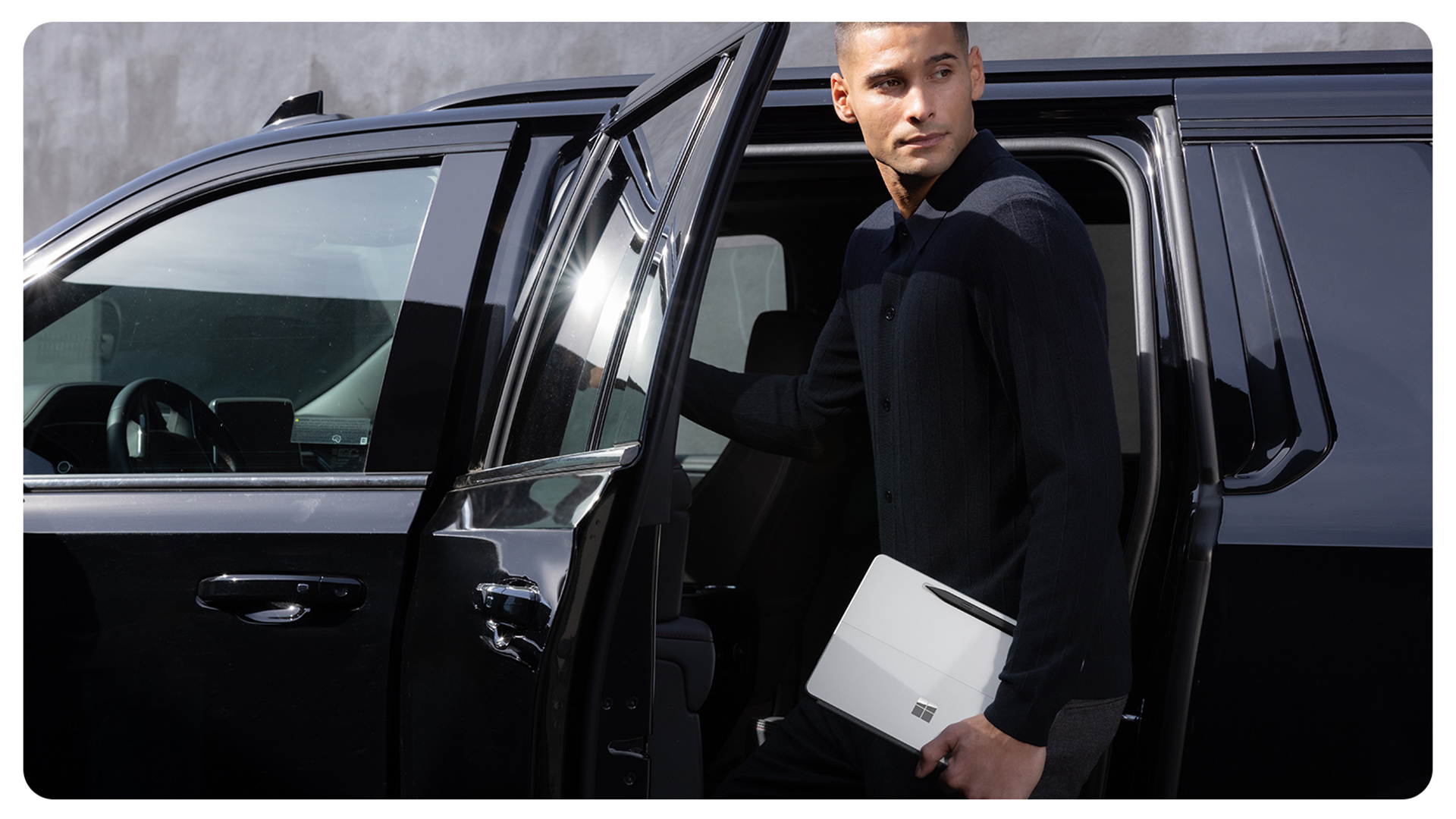 一个人在下车时手持 Surface Pro 商用版。