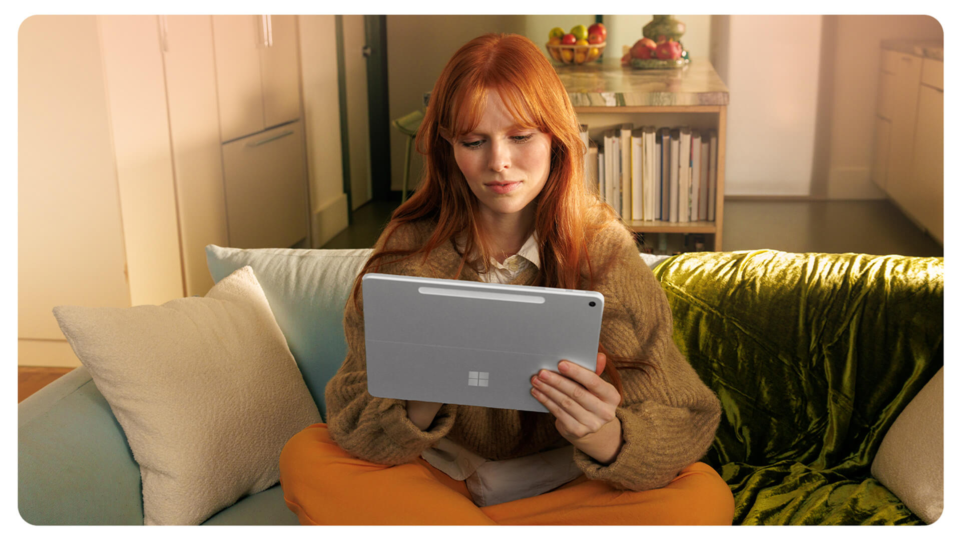 一个人坐在沙发上，手持一台 Surface Pro 商用版。